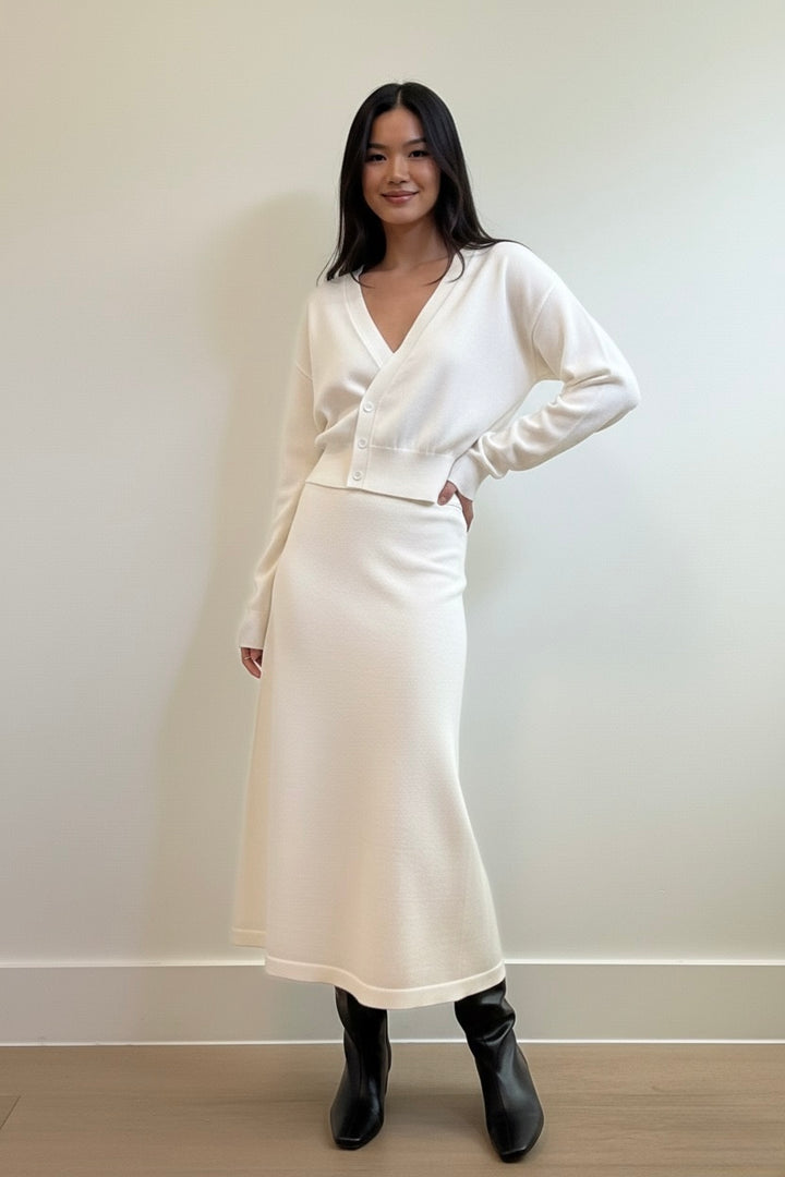 Ivory two-piece knit set featuring a cinched-waist cardigan and a flowy midi skirt. Soft, elegant, and perfect for elevated everyday style.