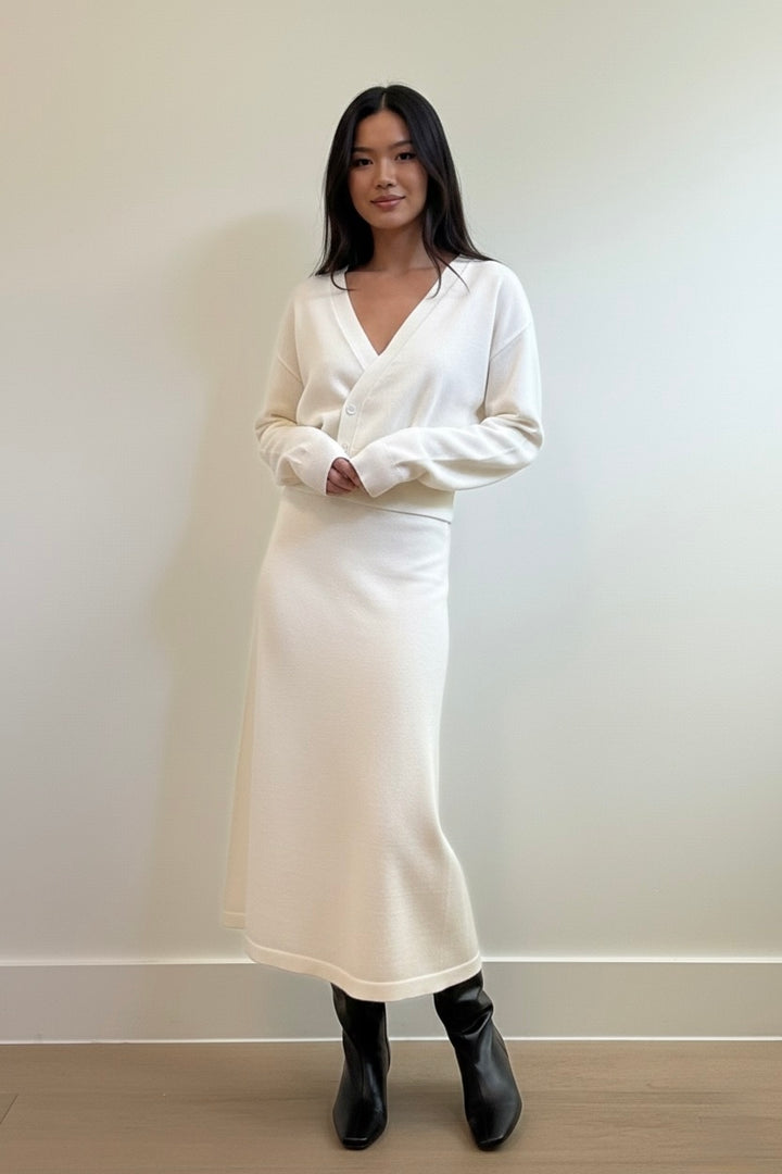 Ivory two-piece knit set featuring a cinched-waist cardigan and a flowy midi skirt. Soft, elegant, and perfect for elevated everyday style.