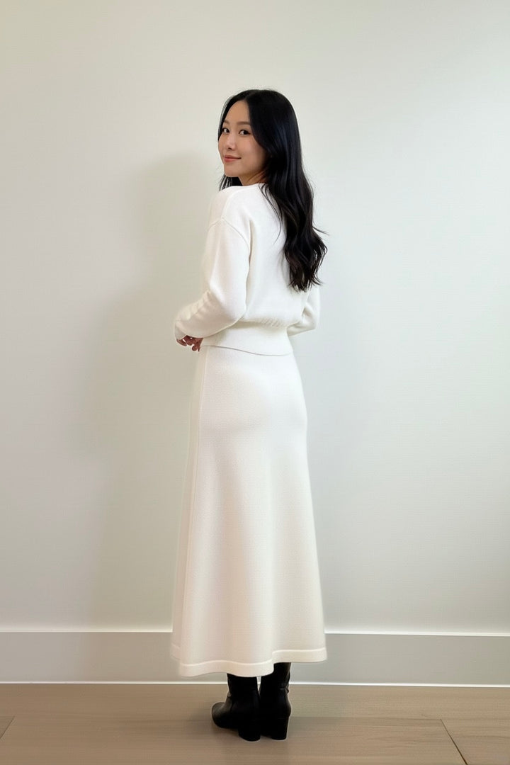 Ivory two-piece knit set featuring a cinched-waist cardigan and a flowy midi skirt. Soft, elegant, and perfect for elevated everyday style.